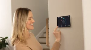 lady on the left adjusting a digital thermostat on the wall