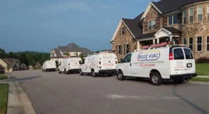 four white Biggs vehicles lined up and parked in front of a customers house