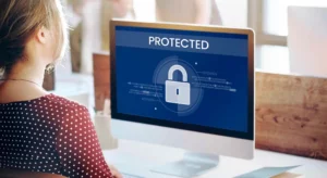 woman sitting at computer and computer screen has the words Protected with an image of a lock