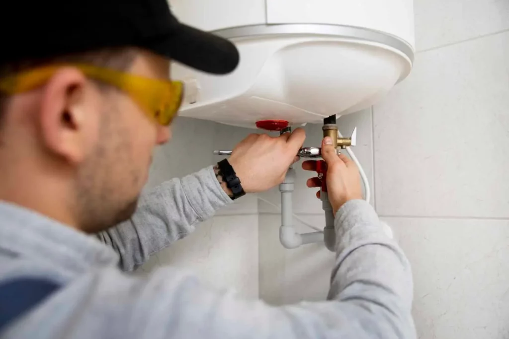 plumber turning wrench on water heater pipes