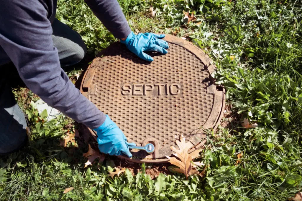 technician using tools to open the lid of a septic tank, words septic on lid